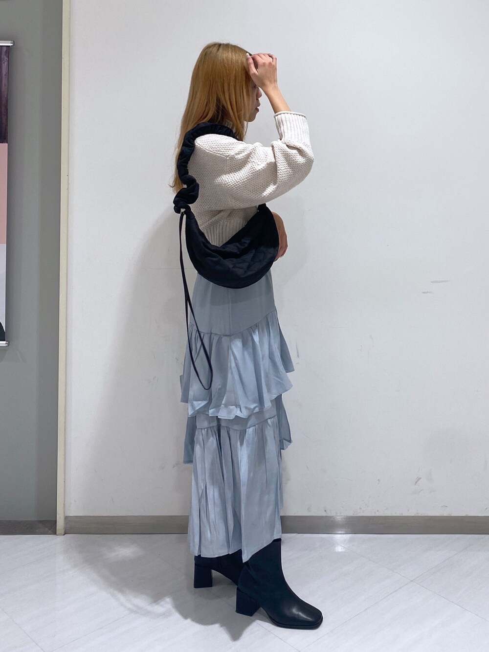 グレー系のスカート、ホワイト系のニット/セーター、ブラック系のブーツを着用したレディースの冬コーディネートの2枚目の写真