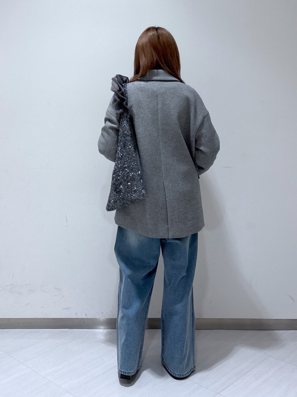 グレー系のピーコート、ホワイト系のニット/セーター、ブルー系のデニムパンツを着用したレディースの冬コーディネートの5枚目の写真