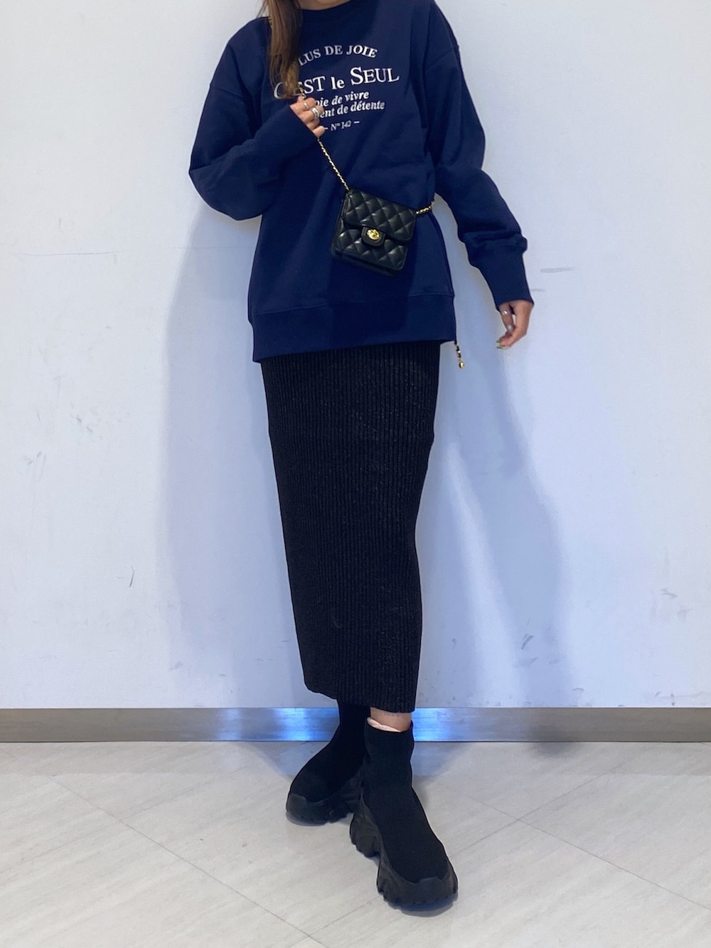 ブルー系のスウェット、ブラック系のスカート、ブラック系のショルダーバッグを着用したレディースの冬コーディネートの3枚目の写真