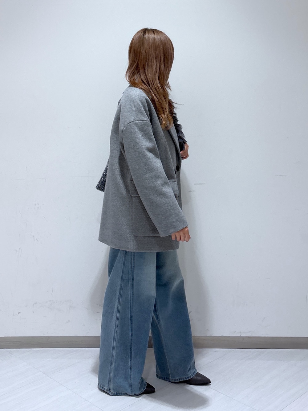 グレー系のピーコート、ホワイト系のニット/セーター、ブルー系のデニムパンツを着用したレディースの冬コーディネートの4枚目の写真