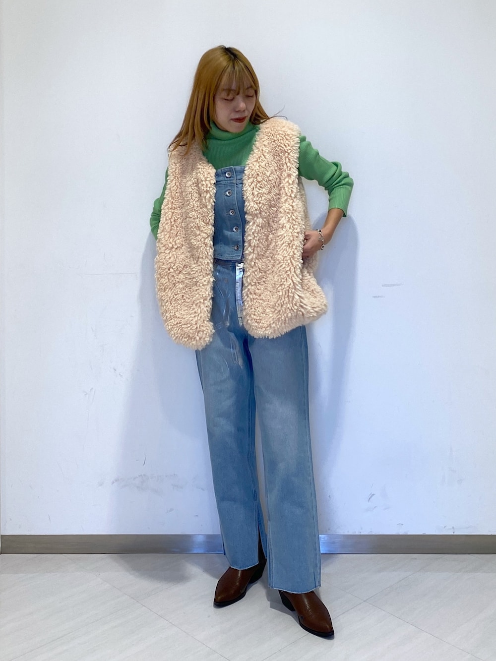 ブルー系のデニムパンツ、グリーン系のニット/セーター、ブルー系のベストを着用したレディースの冬コーディネートの2枚目の写真