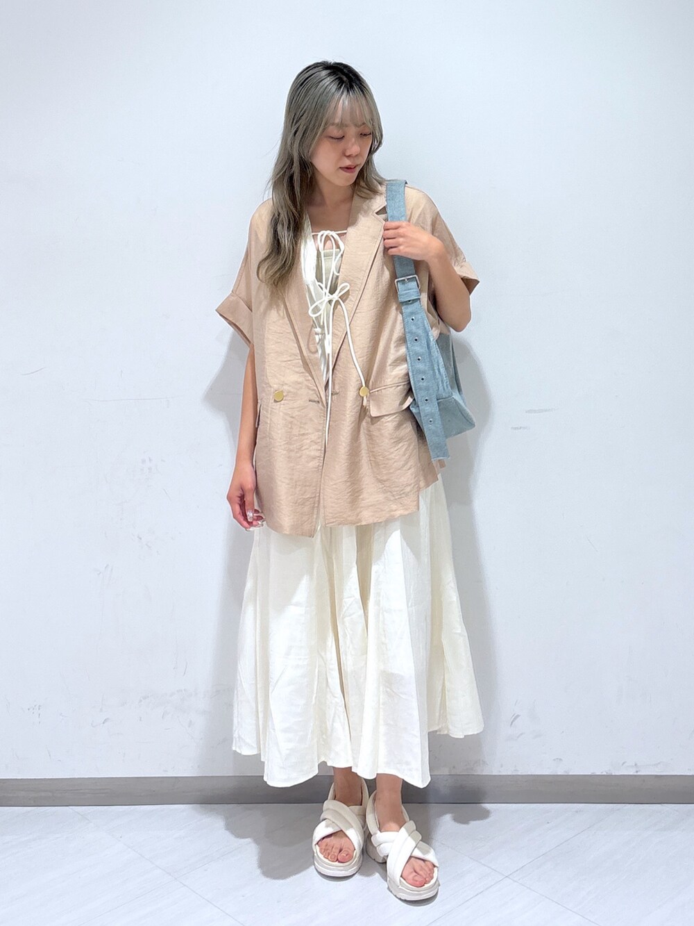 ホワイト系のワンピース、ベージュ系のテーラードジャケット、ブルー系のショルダーバッグを着用したレディースの夏コーディネートの2枚目の写真