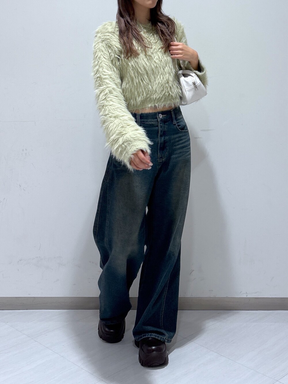 ベージュ系のニット/セーター、ホワイト系のトートバッグ、ブルー系のデニムパンツを着用したレディースの冬コーディネートの3枚目の写真