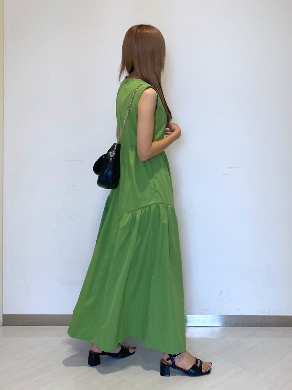 ブラック系のショルダーバッグ、グリーン系のワンピース、ブラック系のサンダルを着用したレディースの夏コーディネートの2枚目の写真
