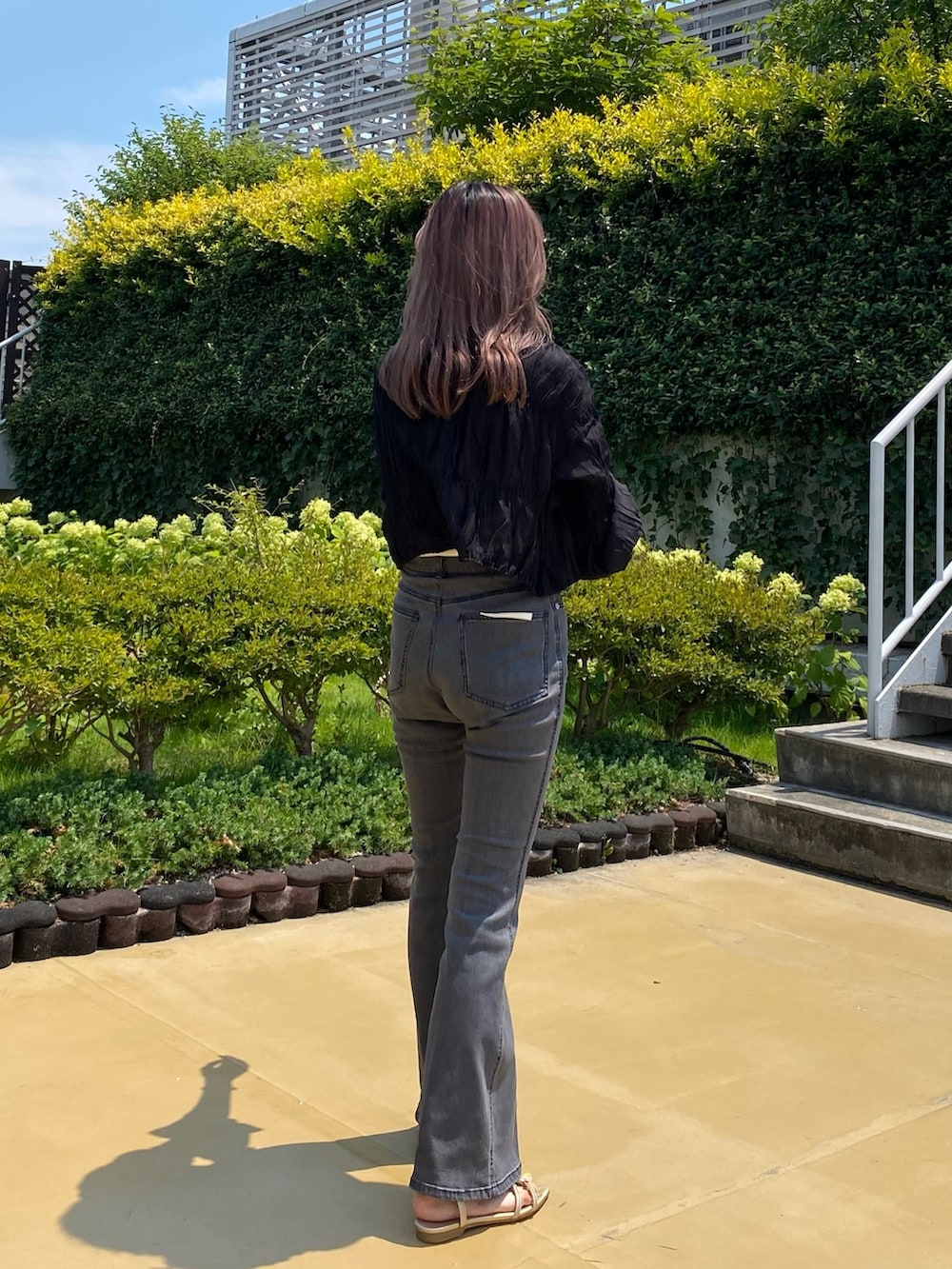 ブラック系のデニムパンツ、ゴールド系のサンダル、ブラック系のシャツ/ブラウスを着用したレディースの夏コーディネートの2枚目の写真