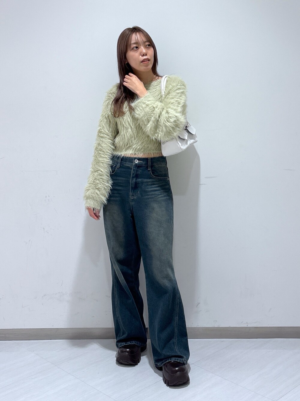 ベージュ系のニット/セーター、ホワイト系のトートバッグ、ブルー系のデニムパンツを着用したレディースの冬コーディネートの2枚目の写真