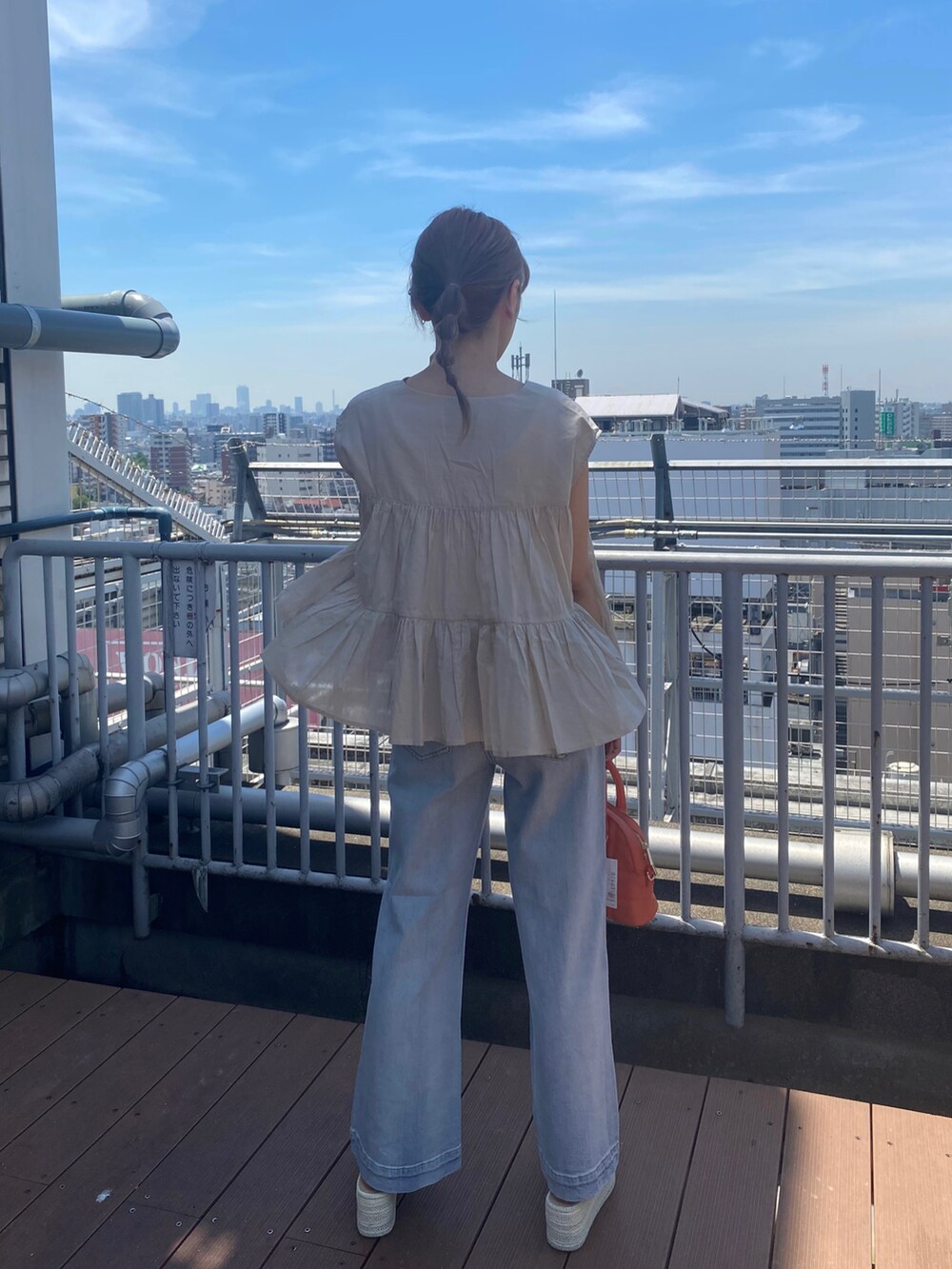 ホワイト系のサンダル、ブルー系のデニムパンツ、オレンジ系のハンドバッグを着用したレディースの夏コーディネートの3枚目の写真