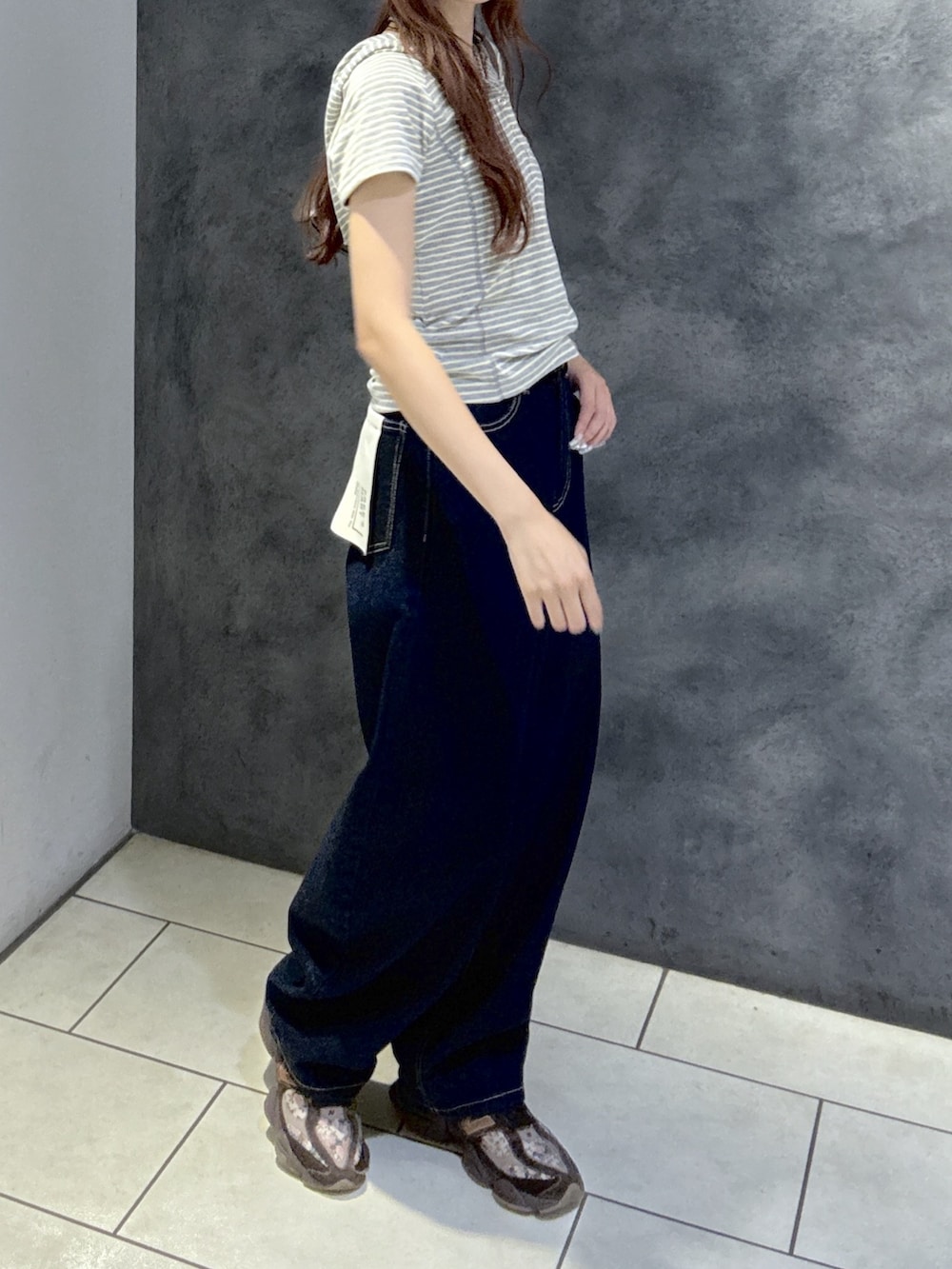グレー系のTシャツ/カットソー、ブラウン系のショルダーバッグ、ブルー系のデニムパンツを着用したレディースの夏コーディネートの4枚目の写真