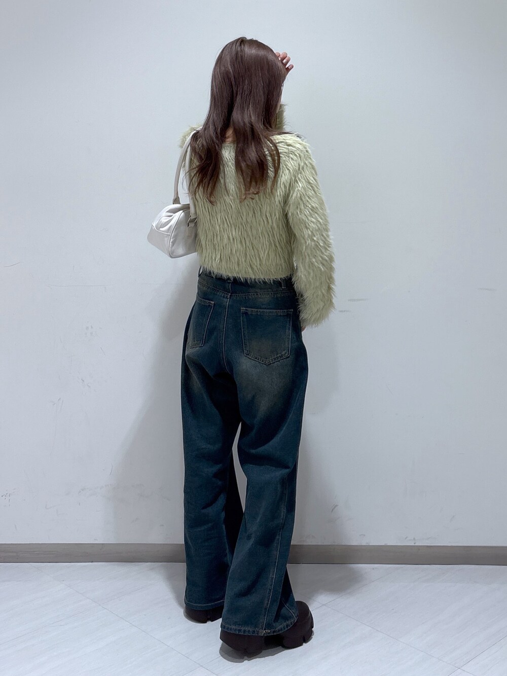 ベージュ系のニット/セーター、ホワイト系のトートバッグ、ブルー系のデニムパンツを着用したレディースの冬コーディネートの4枚目の写真