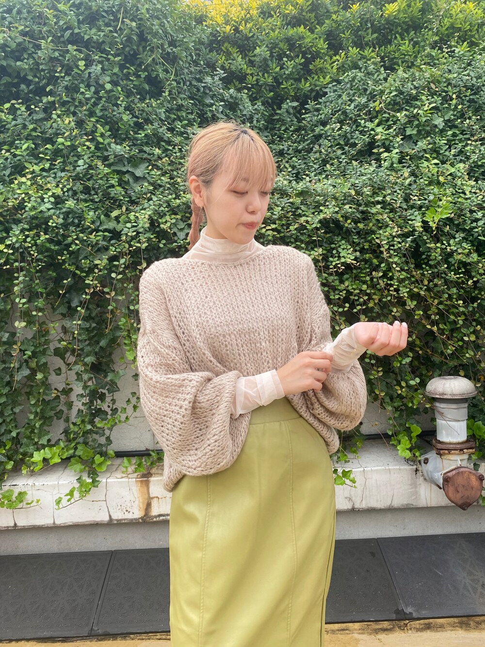 ベージュ系のニット/セーター、グリーン系のスカート、ホワイト系のTシャツ/カットソーを着用したレディースの秋コーディネートの2枚目の写真