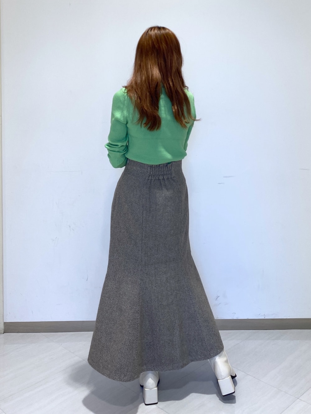 グリーン系のニット/セーター、ベージュ系のスカート、ホワイト系のブーツを着用したレディースの冬コーディネートの2枚目の写真