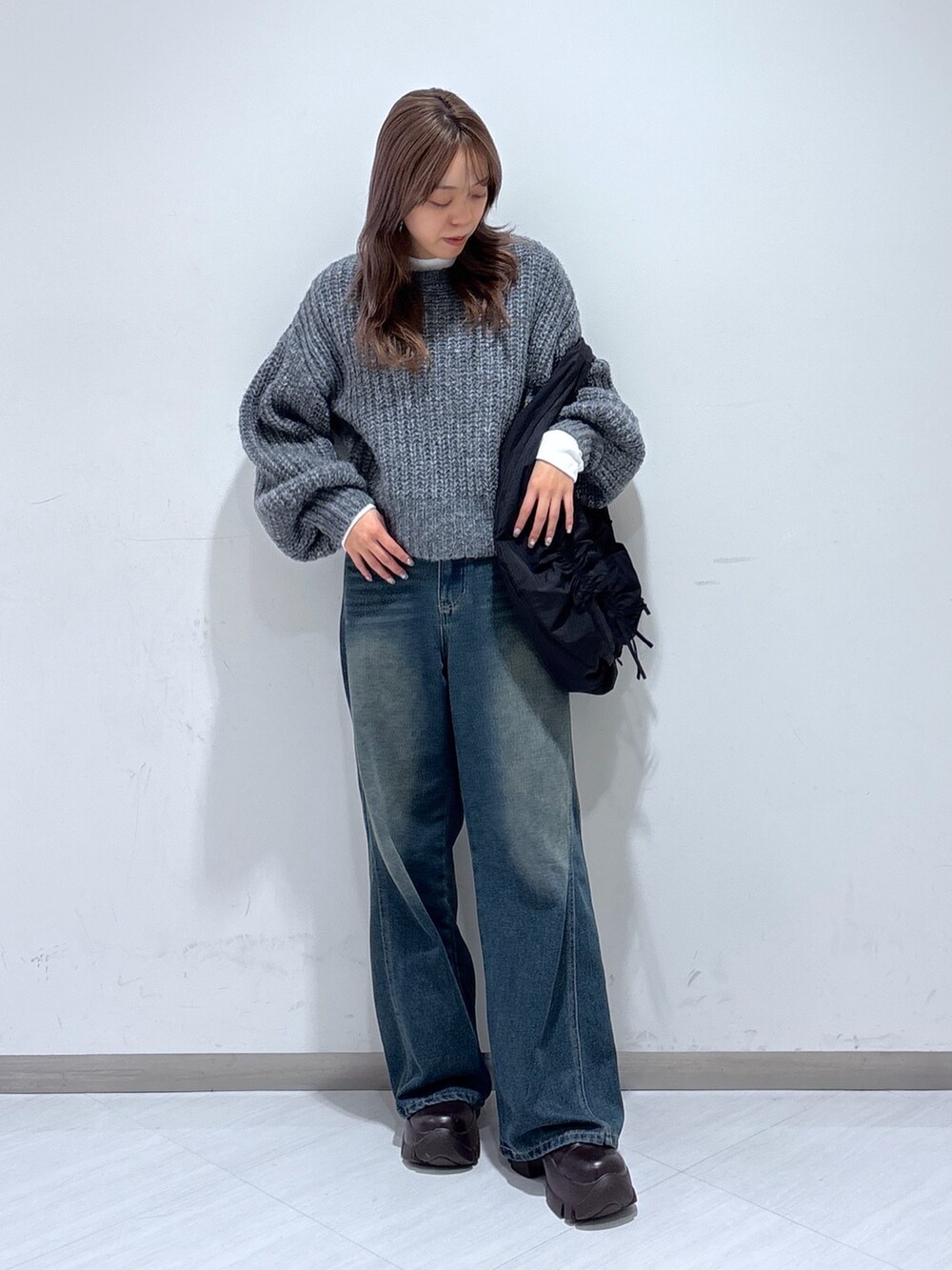 ブラック系のトートバッグ、ブルー系のデニムパンツ、グレー系のニット/セーターを着用したレディースの冬コーディネートの4枚目の写真
