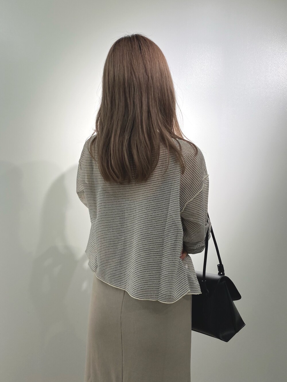 ベージュ系のワンピース、ホワイト系のカーディガン/ボレロ、ブラック系のショルダーバッグを着用したレディースの夏コーディネートの3枚目の写真