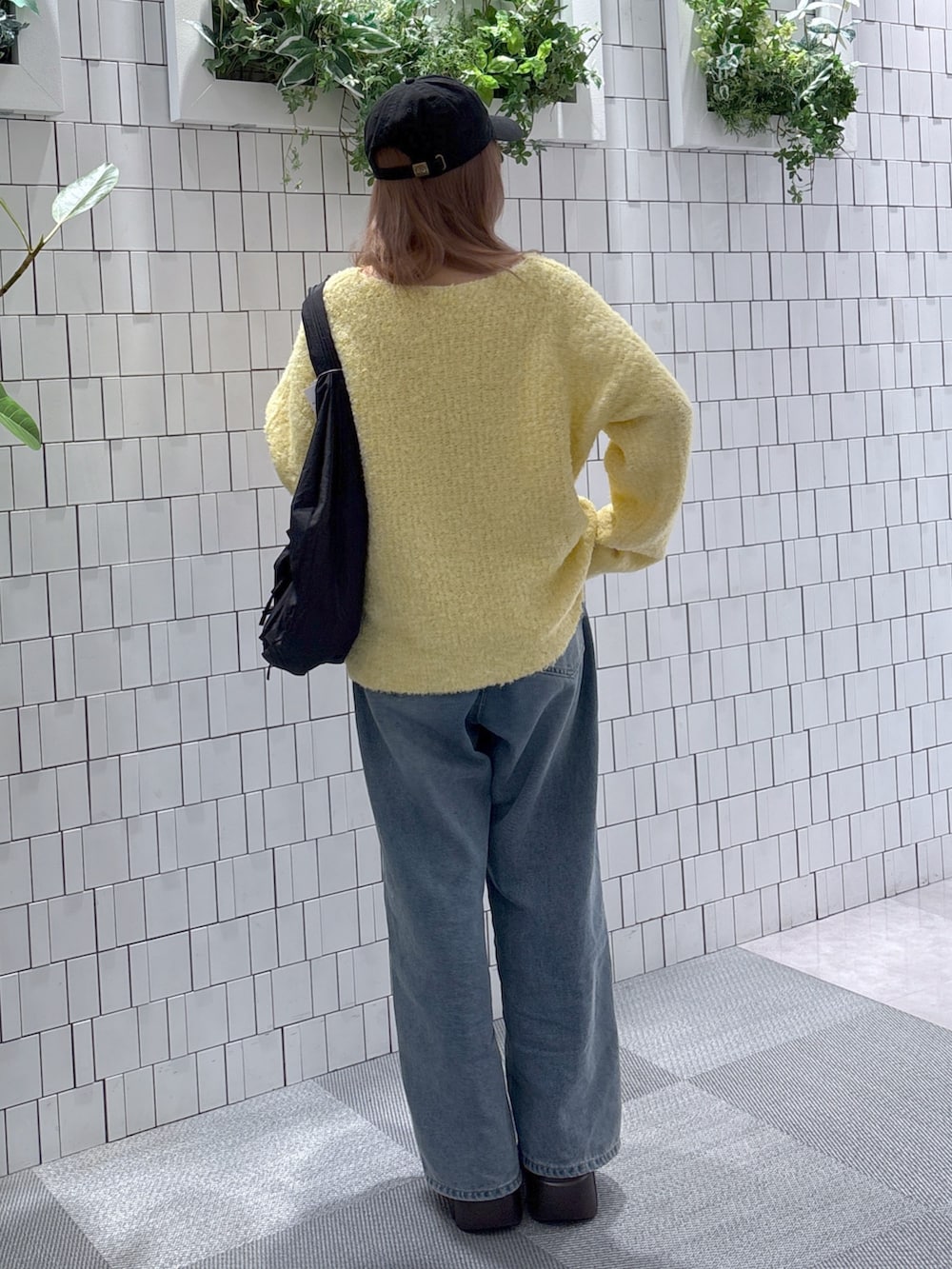 イエロー系のニット/セーター、ブルー系のデニムパンツ、ブラック系のトートバッグを着用したレディースの冬コーディネートの5枚目の写真