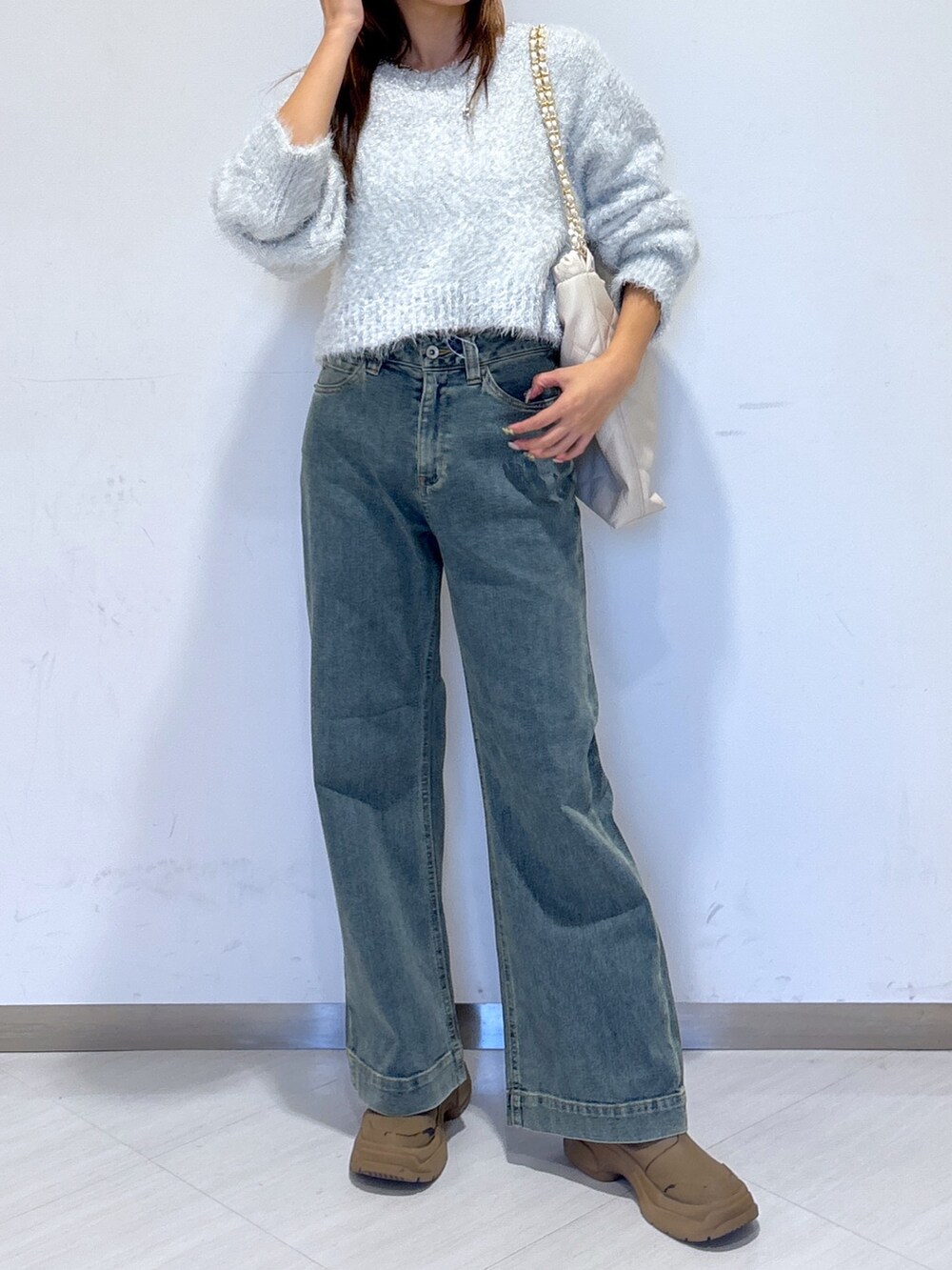 ブルー系のデニムパンツ、ホワイト系のニット/セーター、ホワイト系のトートバッグを着用したレディースの冬コーディネートの3枚目の写真