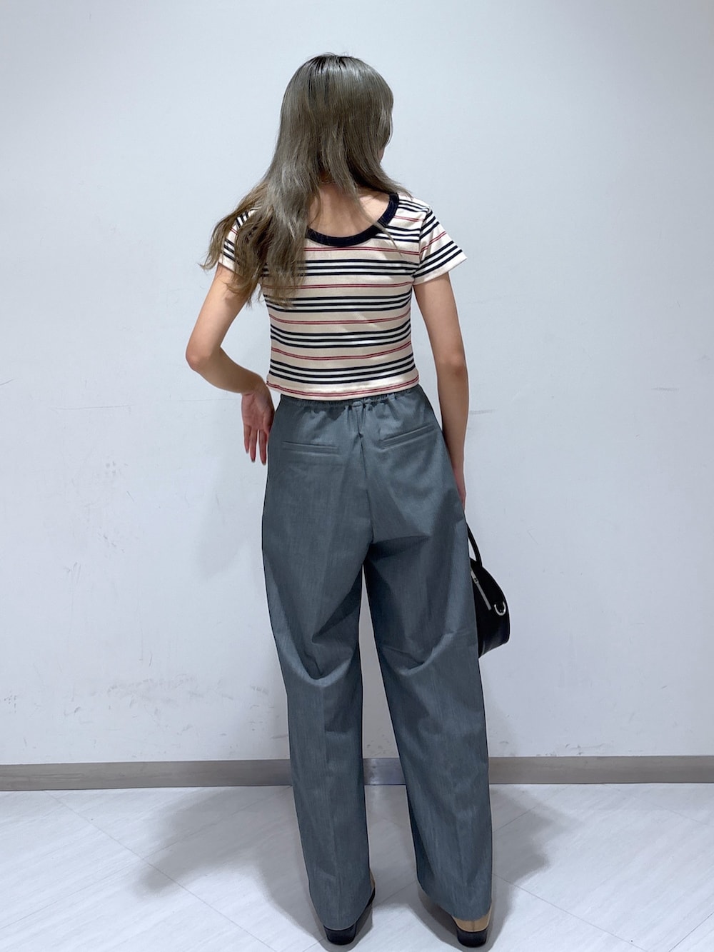 グレー系のスラックス、ホワイト系のTシャツ/カットソー、ブラック系のトートバッグを着用したレディースの夏コーディネートの4枚目の写真