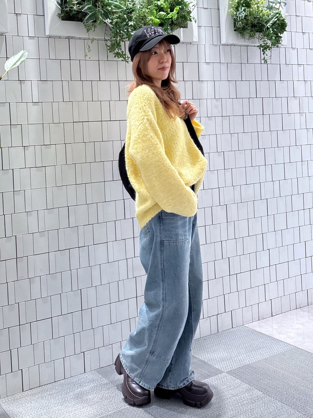 イエロー系のニット/セーター、ブルー系のデニムパンツ、ブラック系のトートバッグを着用したレディースの冬コーディネートの4枚目の写真