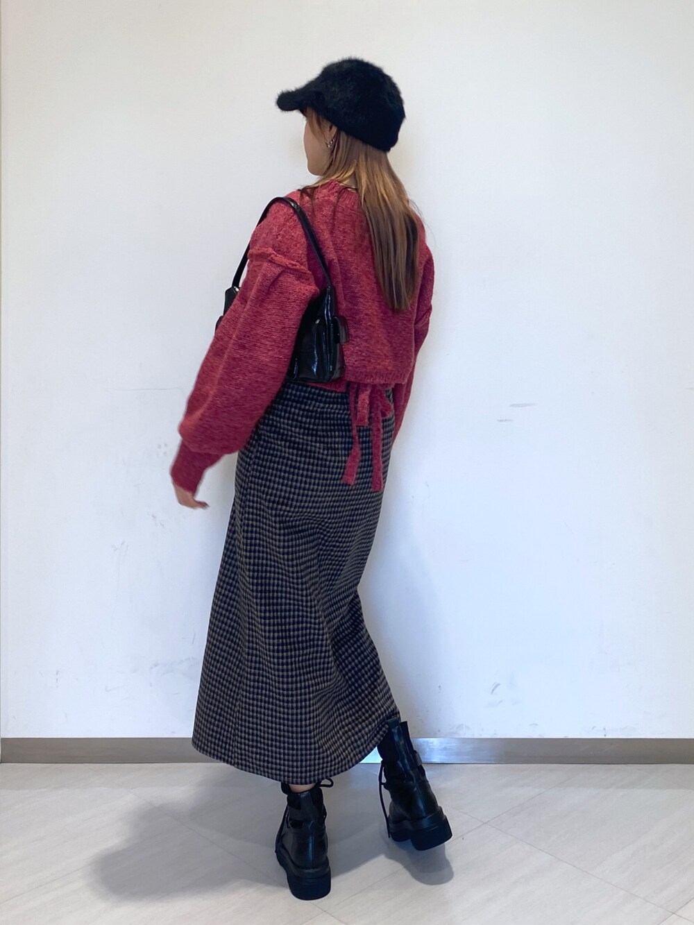 ブラック系のブーツ、ブラック系のハンドバッグ、ピンク系のニット/セーターを着用したレディースの秋コーディネートの4枚目の写真