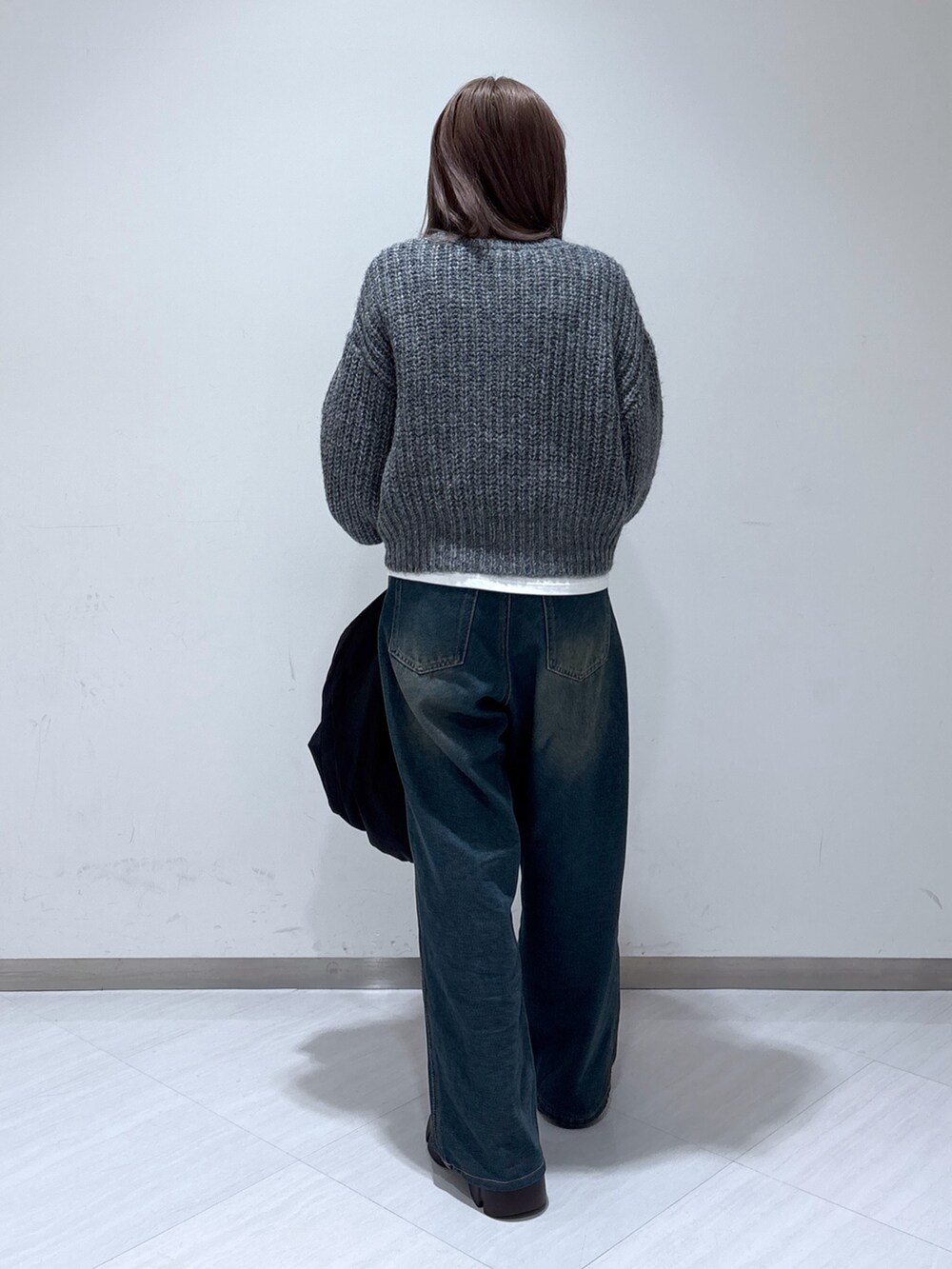 ブラック系のトートバッグ、ブルー系のデニムパンツ、グレー系のニット/セーターを着用したレディースの冬コーディネートの5枚目の写真