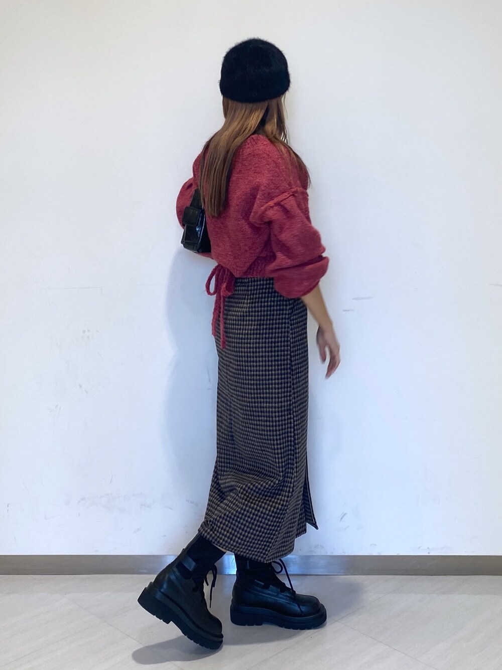 ブラック系のブーツ、ブラック系のハンドバッグ、ピンク系のニット/セーターを着用したレディースの秋コーディネートの3枚目の写真