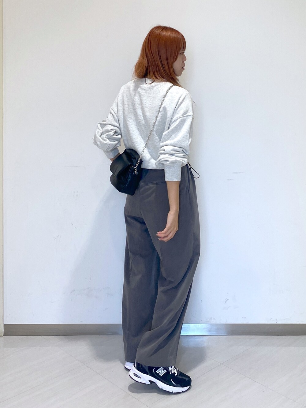 グレー系のスラックス、ホワイト系のTシャツ/カットソー、ブラック系のスニーカーを着用したレディースの秋コーディネートの4枚目の写真