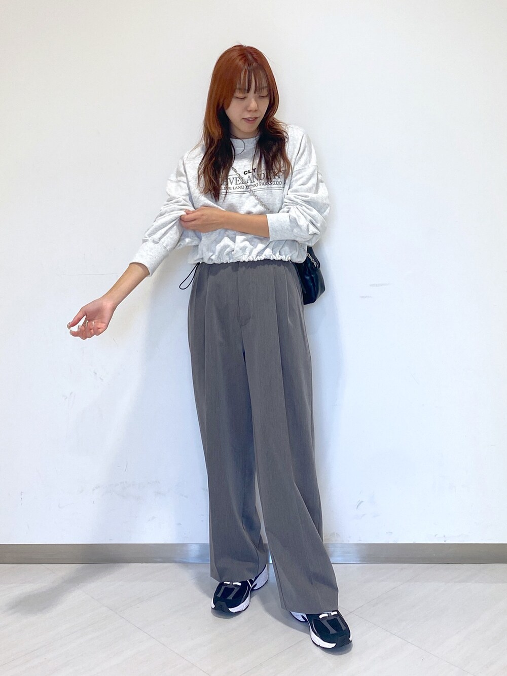 グレー系のスラックス、ホワイト系のTシャツ/カットソー、ブラック系のスニーカーを着用したレディースの秋コーディネートの5枚目の写真