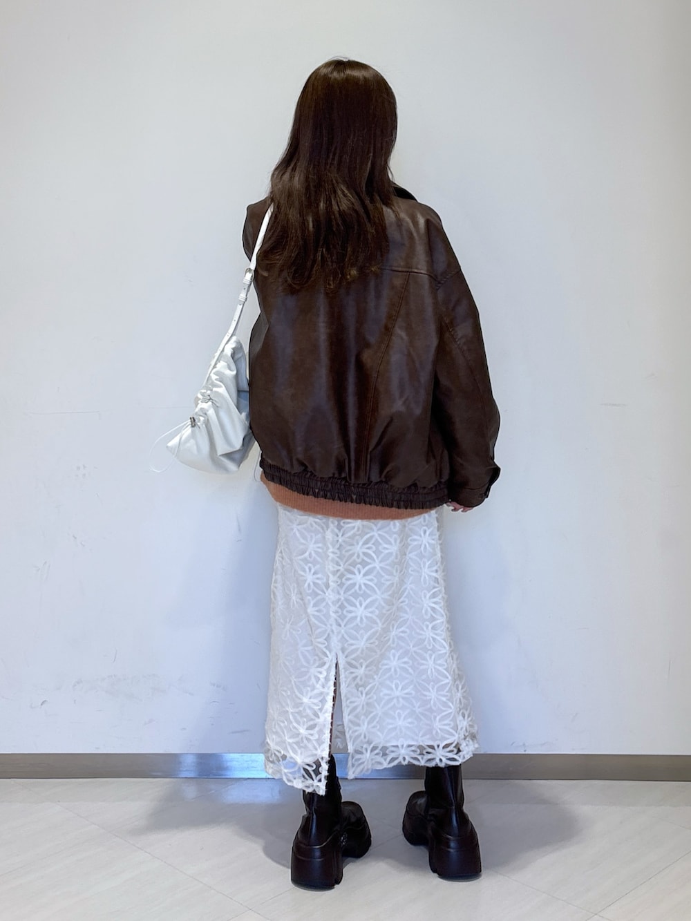 ピンク系のニット/セーター、ホワイト系のスカート、ブラウン系のライダースジャケットを着用したレディースの冬コーディネートの6枚目の写真