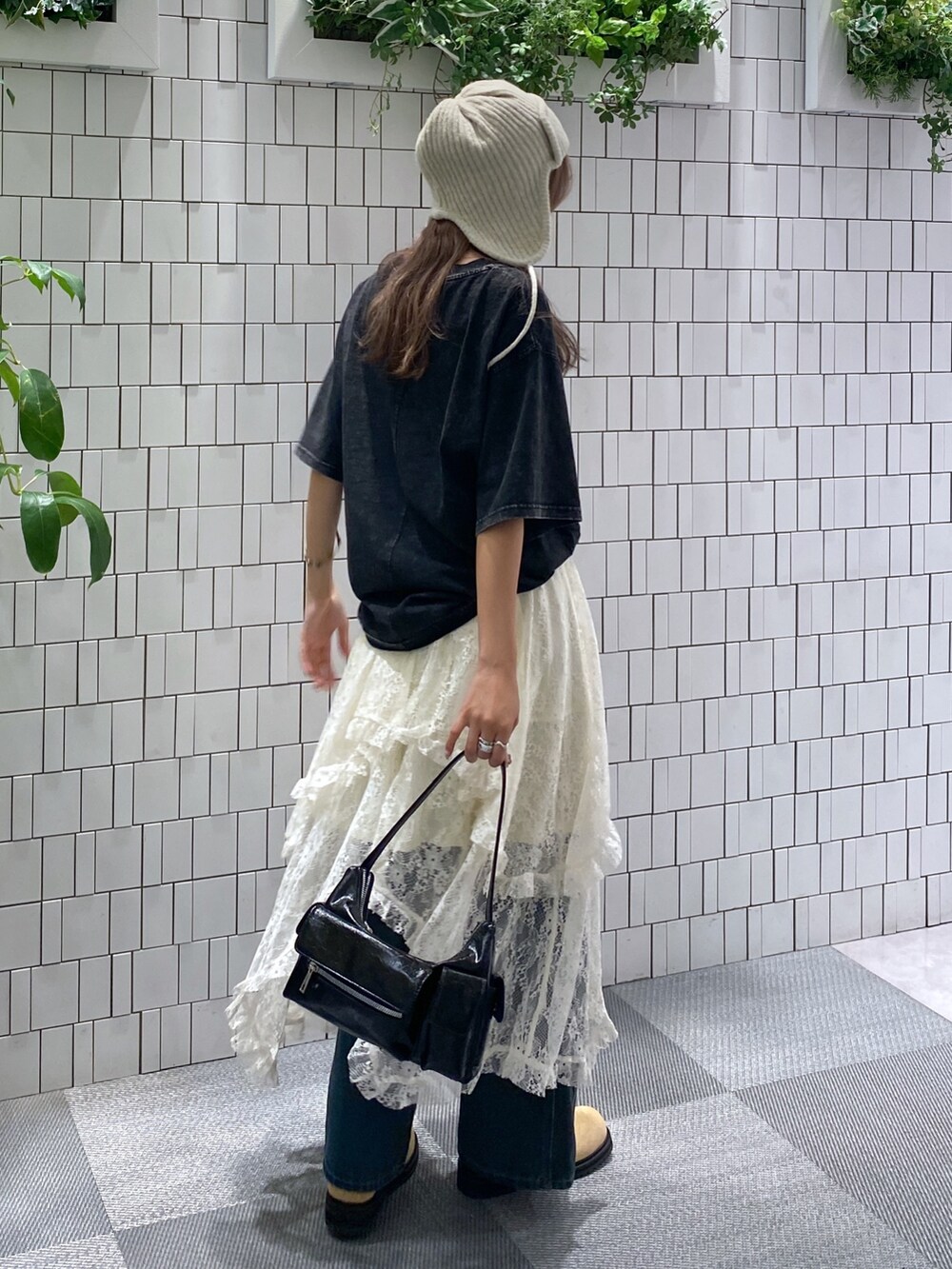 ブラック系のTシャツ/カットソー、ブラック系のハンドバッグ、ホワイト系のスカートを着用したレディースの秋コーディネートの4枚目の写真
