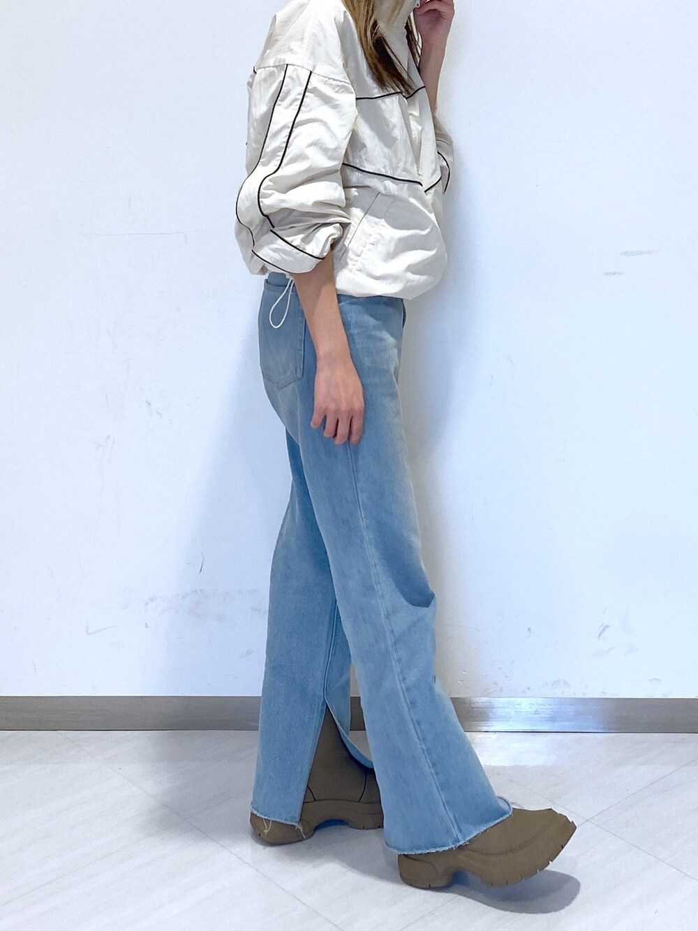 ブルー系のデニムパンツ、ホワイト系のナイロンジャケットを着用したレディースの春コーディネートの2枚目の写真