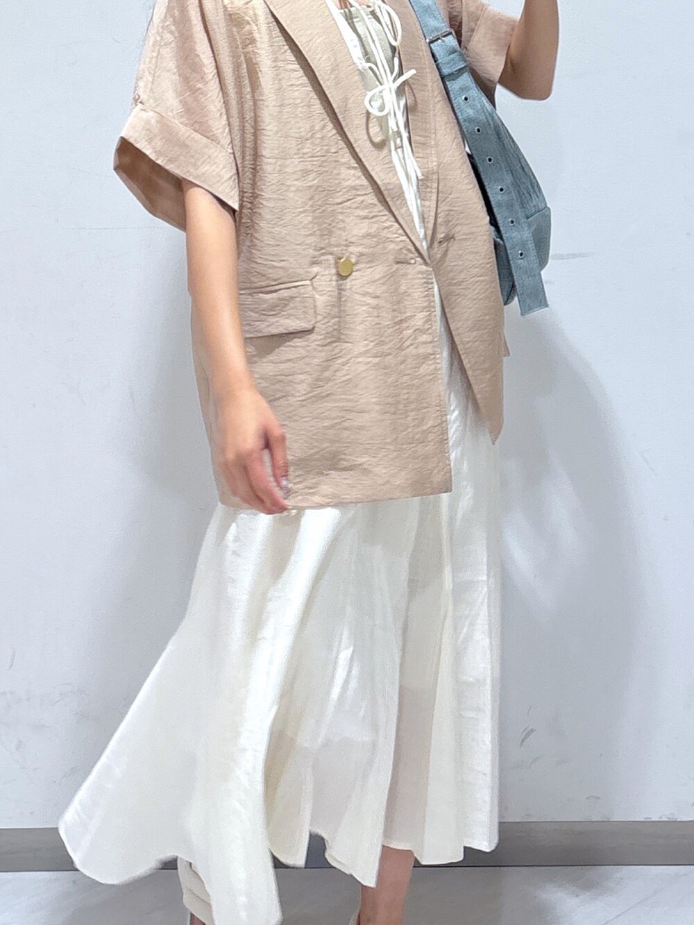 ホワイト系のワンピース、ベージュ系のテーラードジャケット、ブルー系のショルダーバッグを着用したレディースの夏コーディネートの4枚目の写真