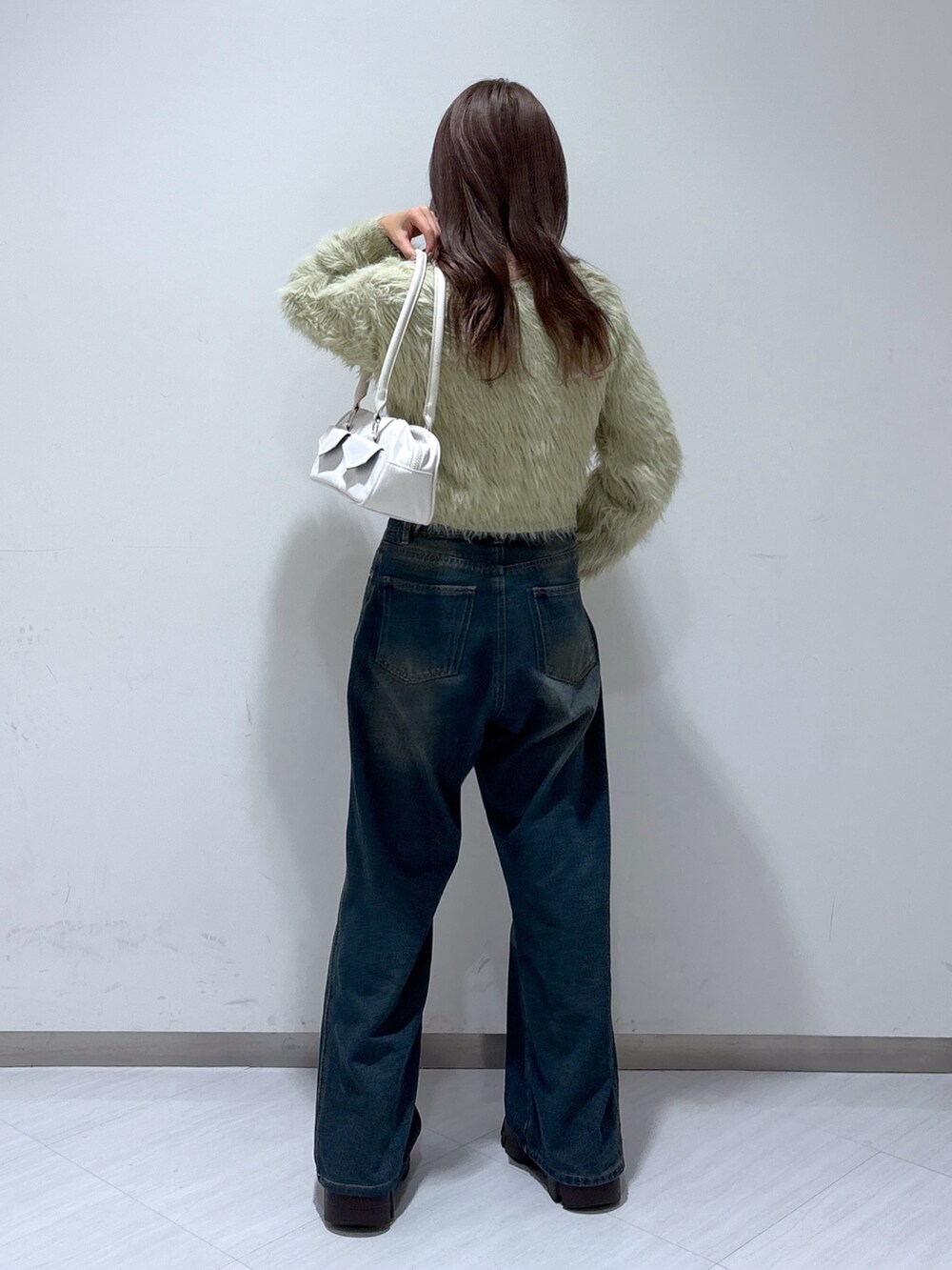 ベージュ系のニット/セーター、ホワイト系のトートバッグ、ブルー系のデニムパンツを着用したレディースの冬コーディネートの6枚目の写真