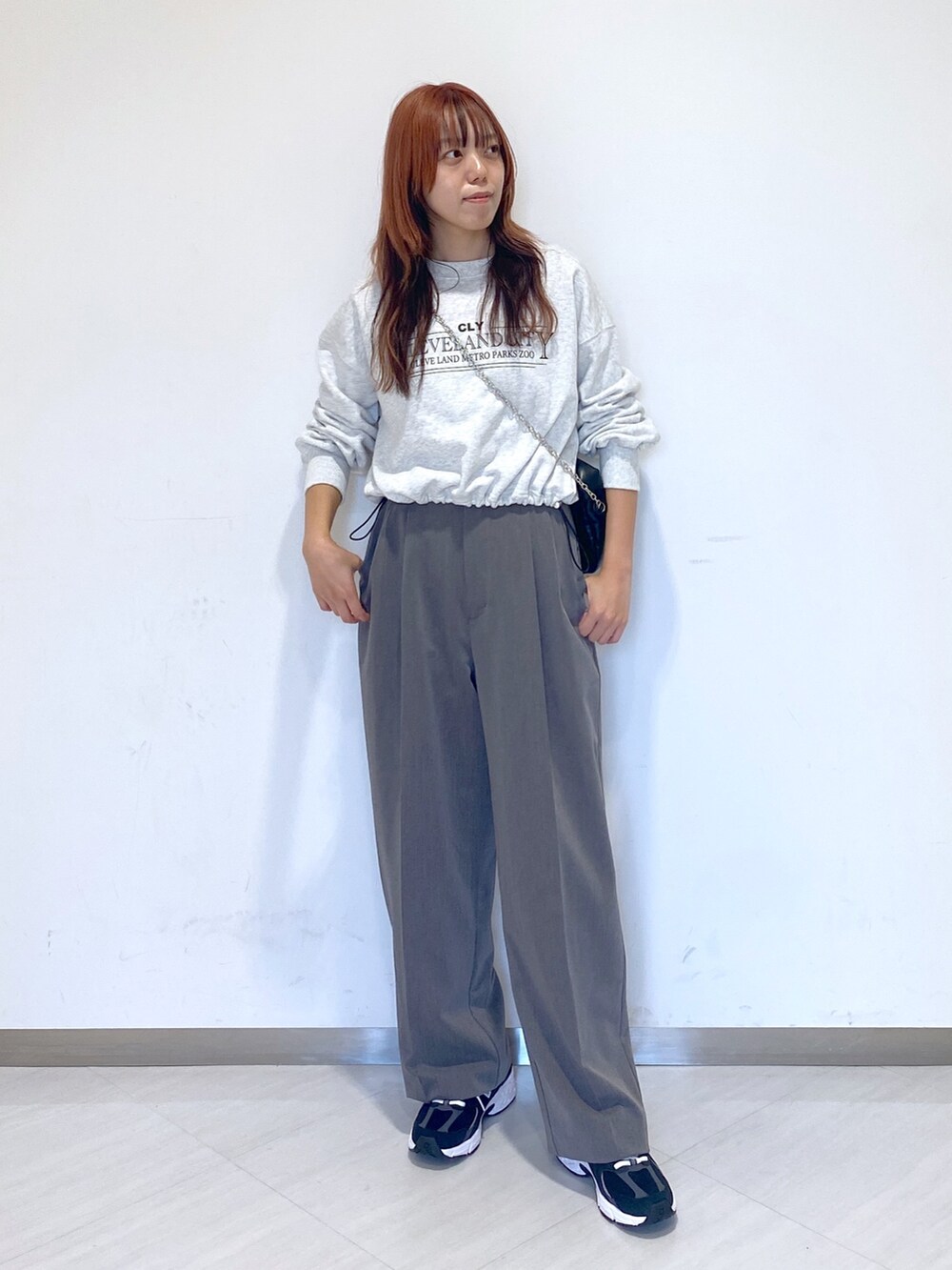 グレー系のスラックス、ホワイト系のTシャツ/カットソー、ブラック系のスニーカーを着用したレディースの秋コーディネートの2枚目の写真