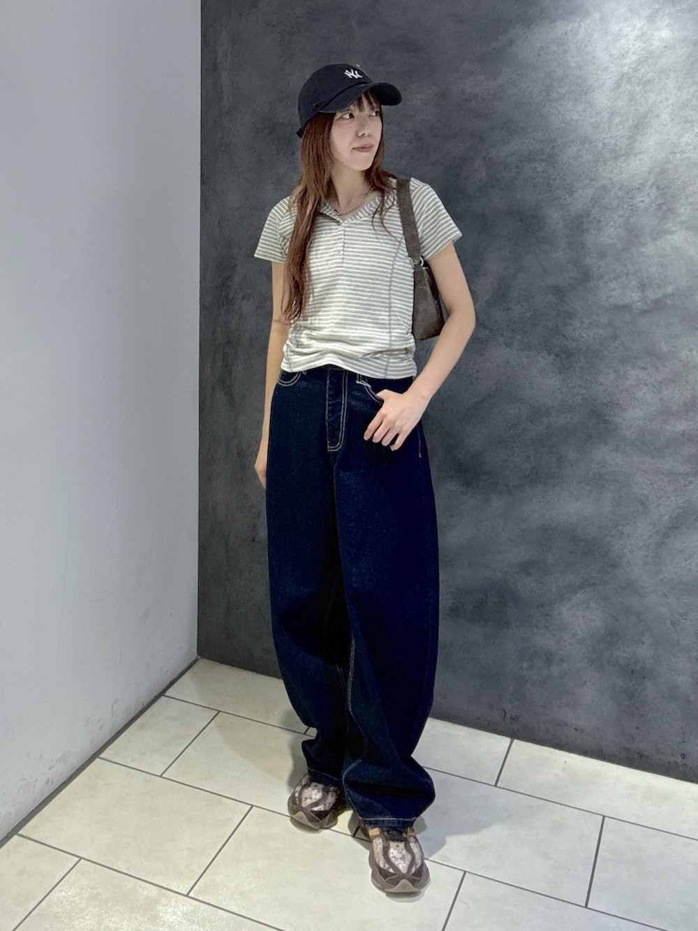 グレー系のTシャツ/カットソー、ブラウン系のショルダーバッグ、ブルー系のデニムパンツを着用したレディースの夏コーディネートの2枚目の写真