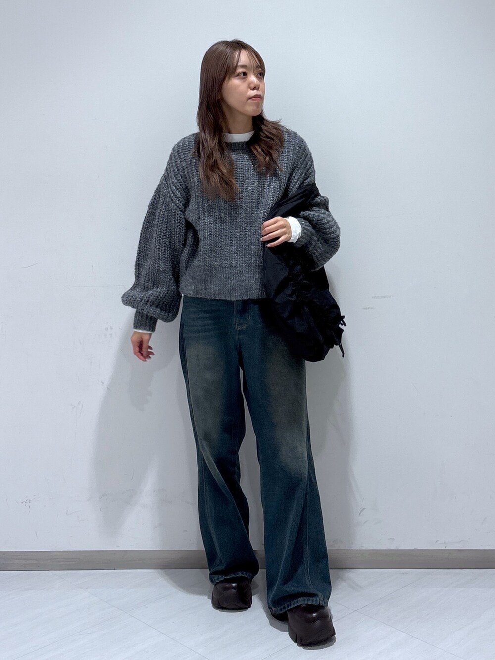 ブラック系のトートバッグ、ブルー系のデニムパンツ、グレー系のニット/セーターを着用したレディースの冬コーディネートの3枚目の写真
