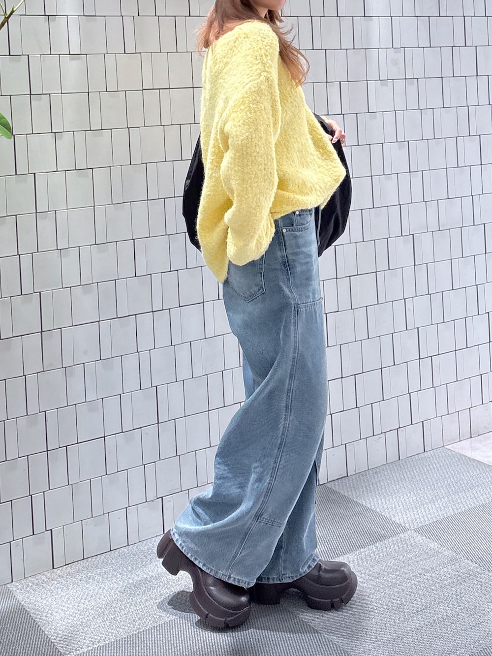 イエロー系のニット/セーター、ブルー系のデニムパンツ、ブラック系のトートバッグを着用したレディースの冬コーディネートの3枚目の写真