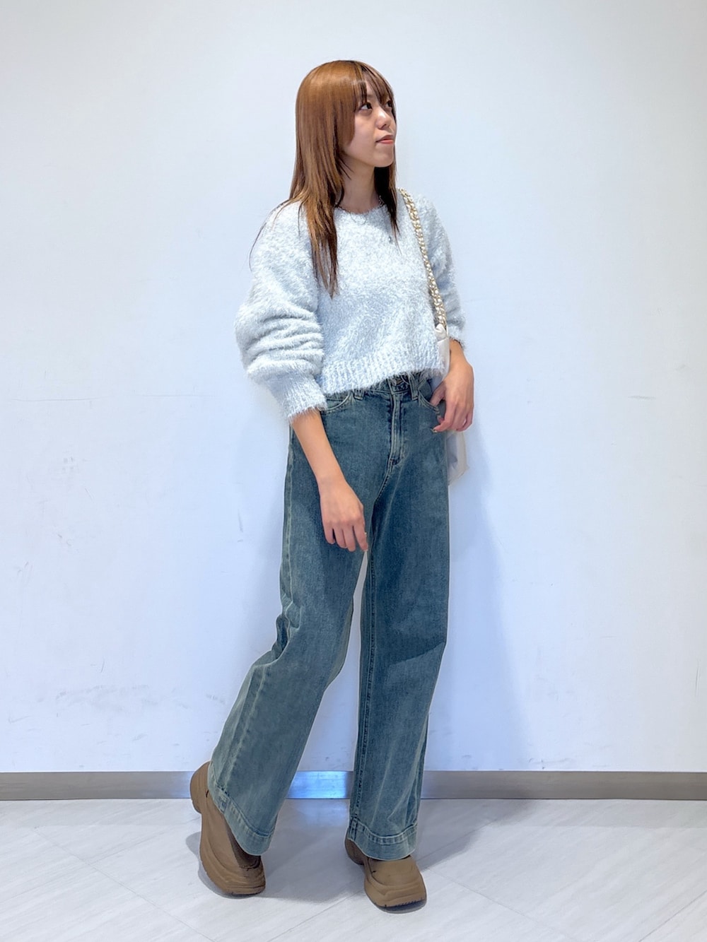 ブルー系のデニムパンツ、ホワイト系のニット/セーター、ホワイト系のトートバッグを着用したレディースの冬コーディネートの2枚目の写真