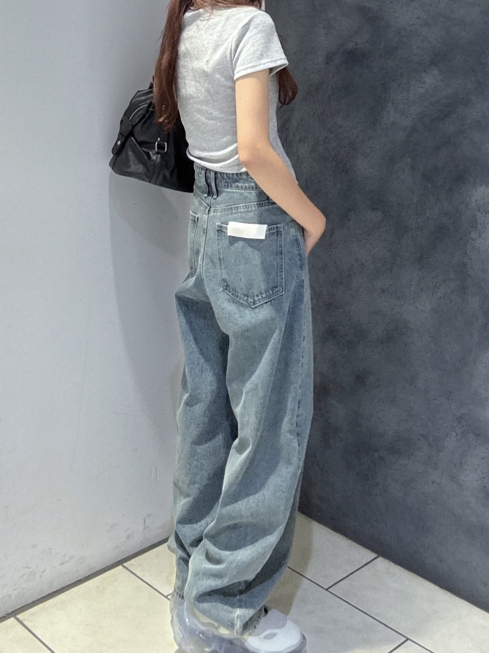 ブラック系のショルダーバッグ、グレー系のTシャツ/カットソー、ブルー系のデニムパンツを着用したレディースの夏コーディネートの3枚目の写真