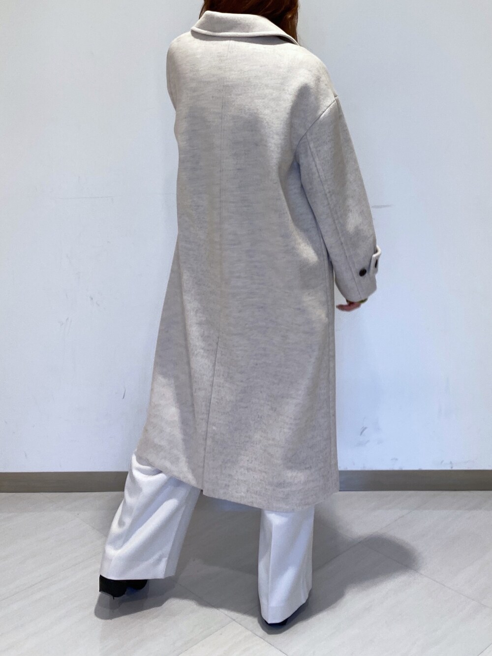 グリーン系のニット/セーター、ホワイト系のスラックス、ベージュ系のチェスターコートを着用したレディースの冬コーディネートの2枚目の写真