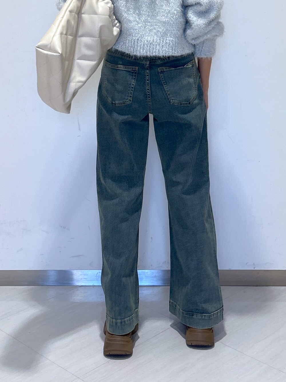 ブルー系のデニムパンツ、ホワイト系のニット/セーター、ホワイト系のトートバッグを着用したレディースの冬コーディネートの5枚目の写真