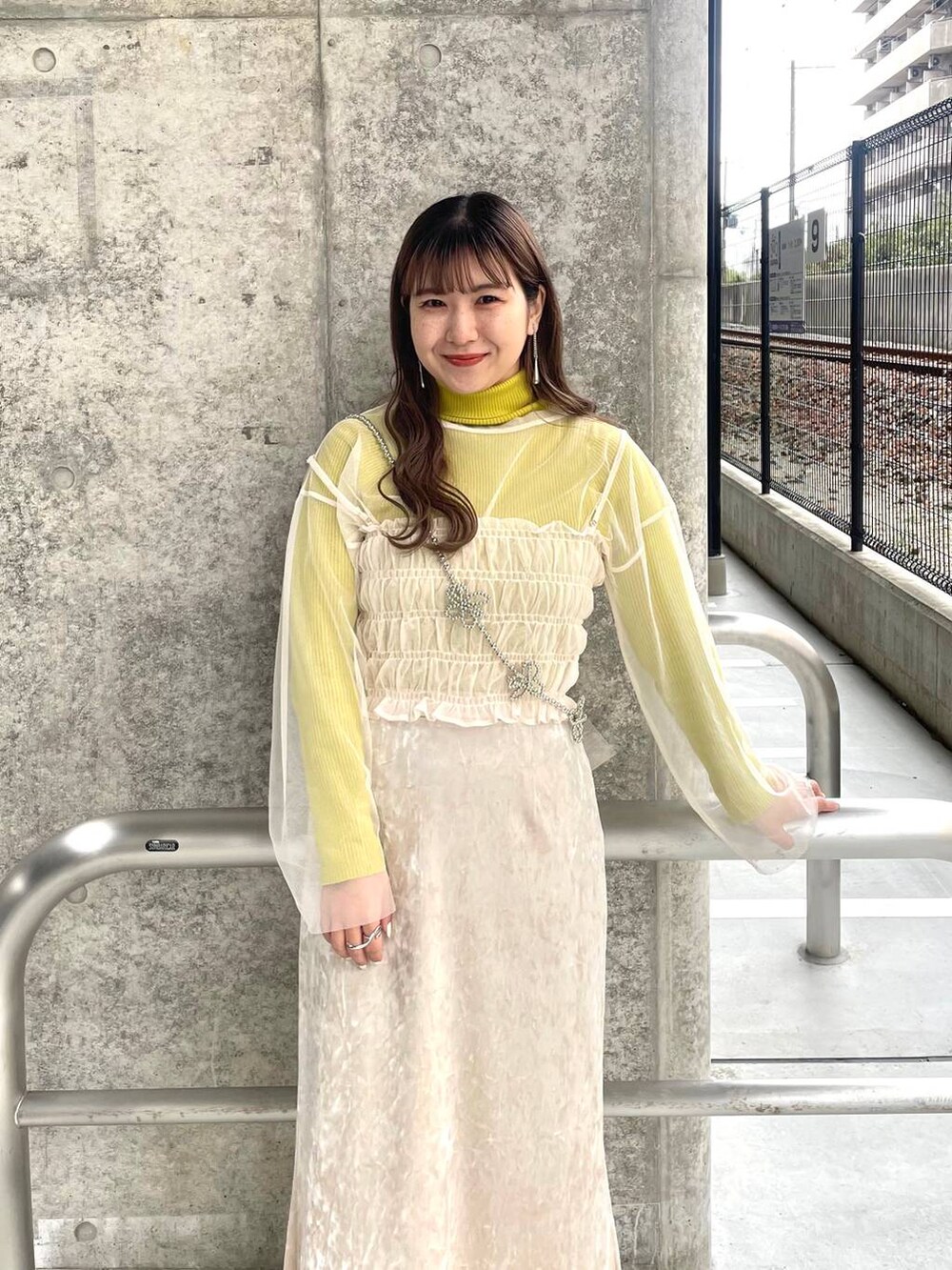 ホワイト系のスカート、ホワイト系のTシャツ/カットソー、グレー系のスマホグッズを着用したレディースの春コーディネートの2枚目の写真