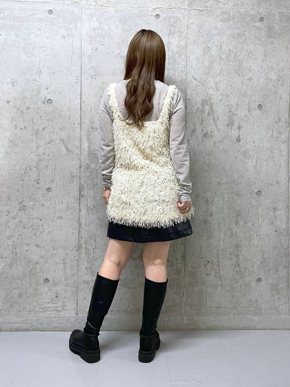 ブラック系のスカート、ブラック系のブーツ、ホワイト系のTシャツ/カットソーを着用したレディースの冬コーディネートの3枚目の写真