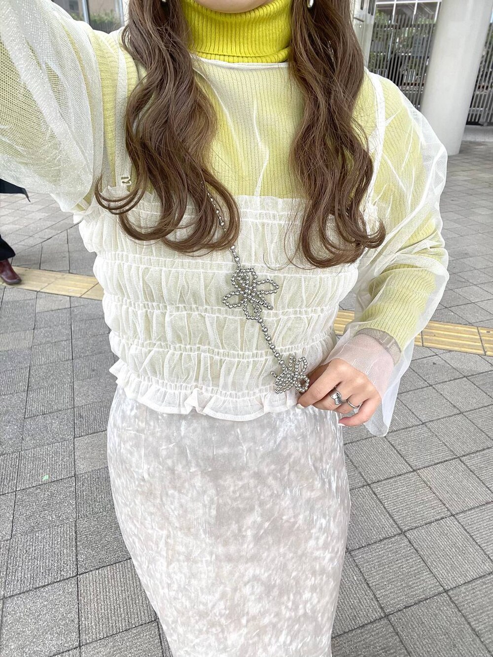 ホワイト系のスカート、ホワイト系のTシャツ/カットソー、グレー系のスマホグッズを着用したレディースの春コーディネートの4枚目の写真