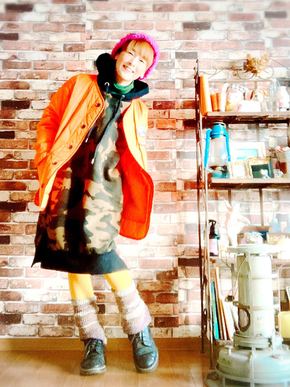 オレンジ系のその他アウター、グリーン系のワンピース、ブラック系のブーツを着用したレディースの冬コーディネートの2枚目の写真