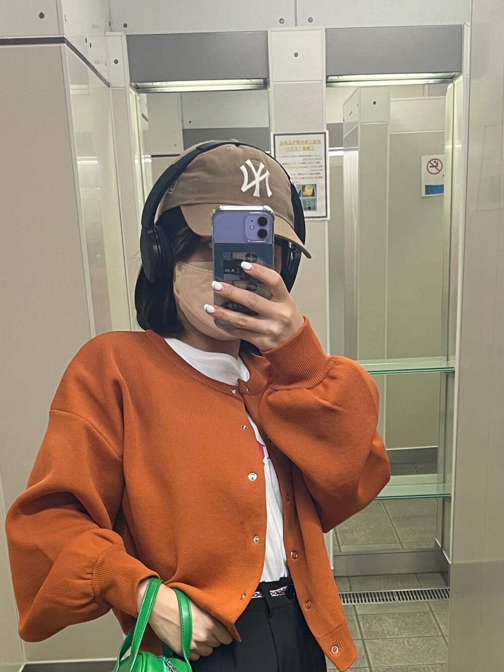 オレンジ系のカーディガン/ボレロ、ホワイト系のTシャツ/カットソー、ブラック系のスニーカーを着用したレディースの春コーディネートの2枚目の写真