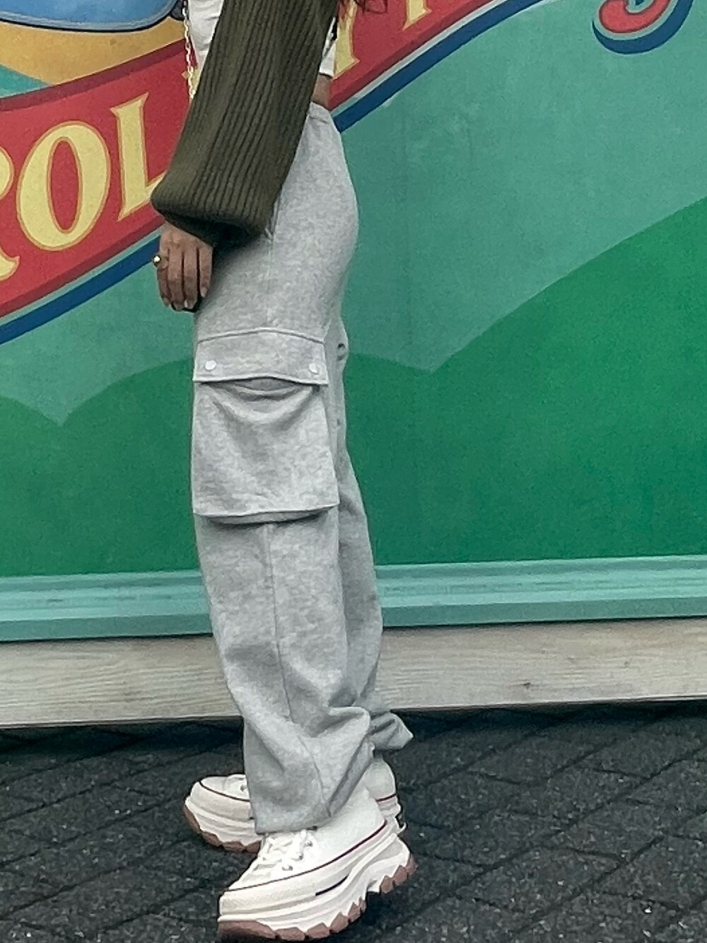 グレー系のスウェットパンツ、グリーン系のニット/セーター、ホワイト系のスニーカーを着用したレディースの冬コーディネートの2枚目の写真