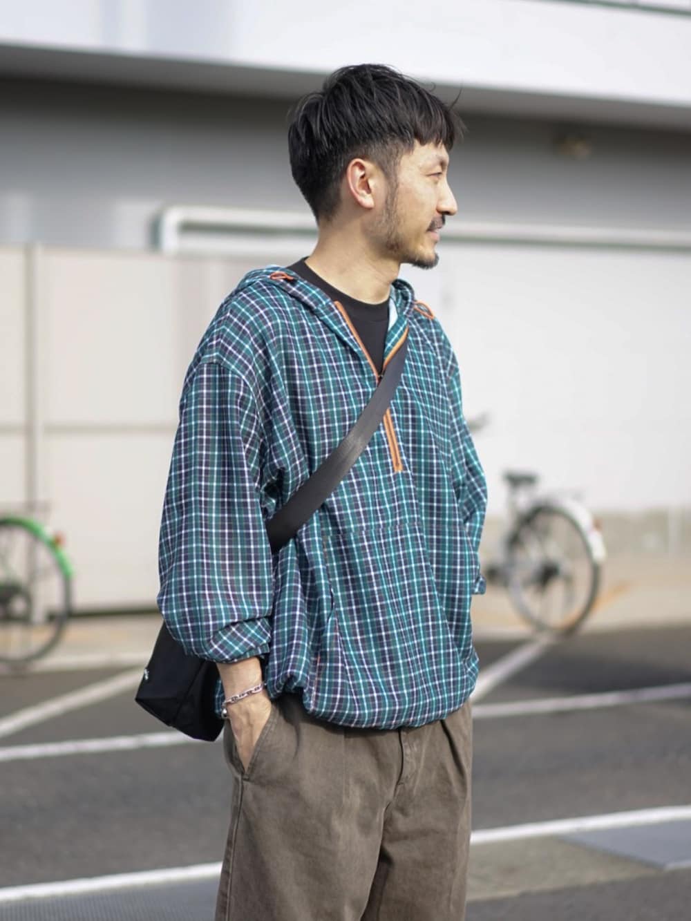 グリーン系のパーカー、ブラウン系のデニムパンツ、ベージュ系のスニーカーを着用したメンズの秋コーディネートの3枚目の写真