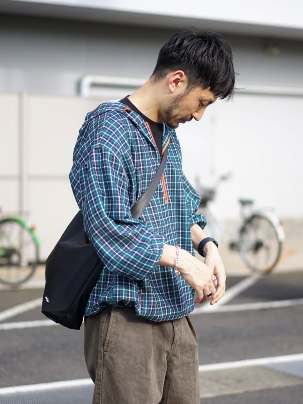 グリーン系のパーカー、ブラウン系のデニムパンツ、ベージュ系のスニーカーを着用したメンズの秋コーディネートの4枚目の写真