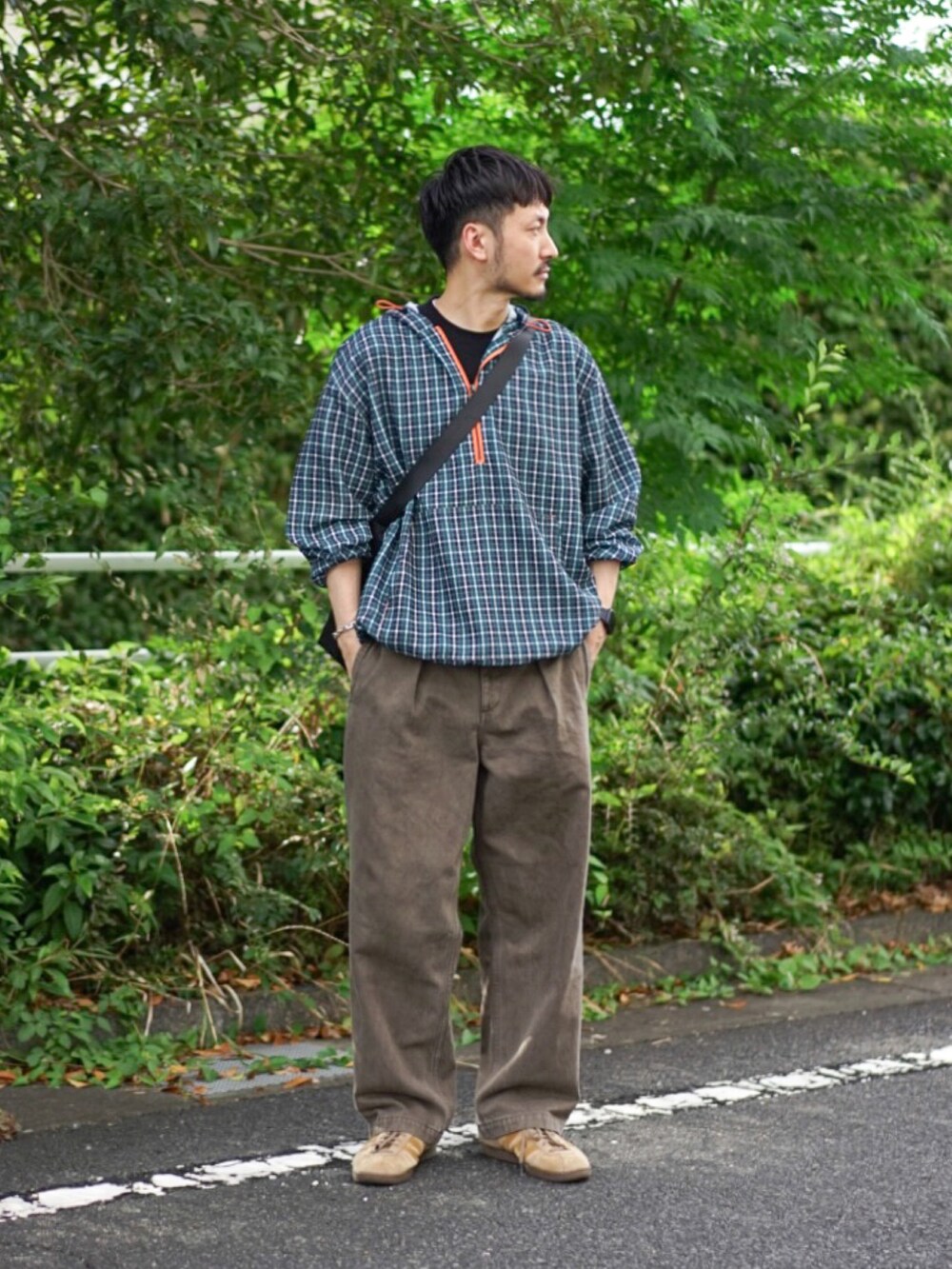 グリーン系のパーカー、ブラウン系のデニムパンツ、ベージュ系のスニーカーを着用したメンズの秋コーディネートの2枚目の写真