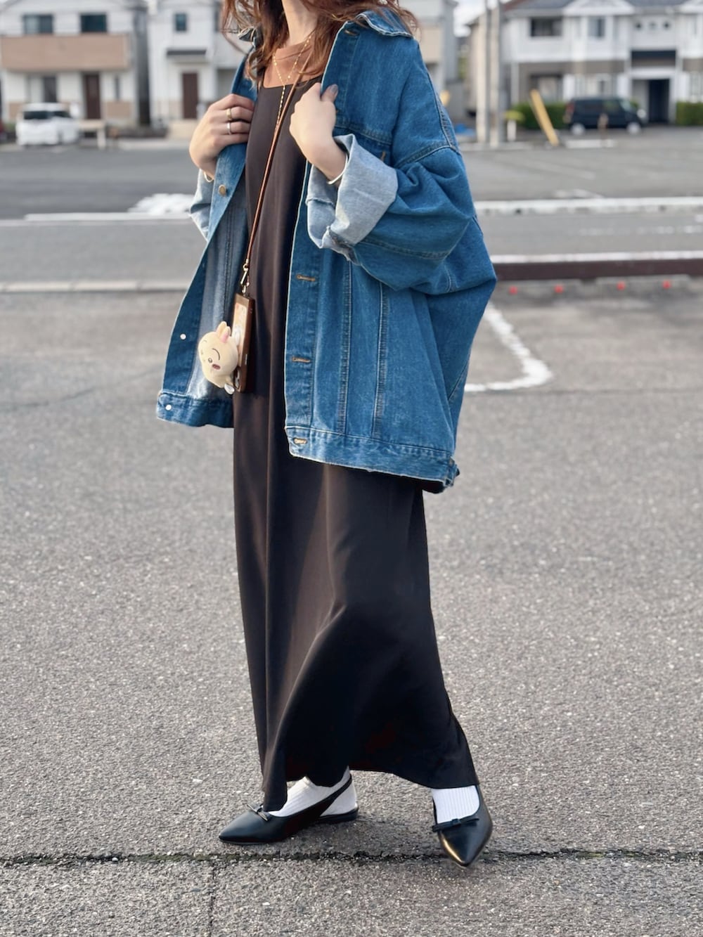ブルー系のデニムジャケット、ブラック系のワンピース、ブラック系のパンプスを着用したレディースの春コーディネートの2枚目の写真