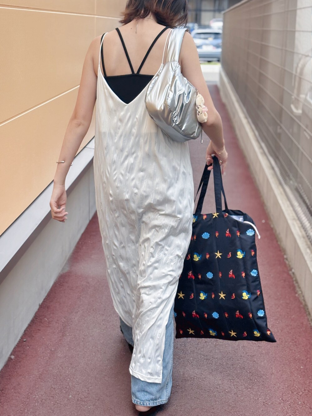 ホワイト系のワンピース、ブルー系のデニムパンツ、ブラック系のサンダルを着用したレディースの夏コーディネートの2枚目の写真